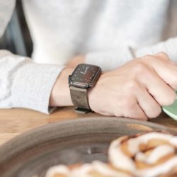 Deep-Leaf-AW-green-full-grain-leather-band-with-hand-on-wood-table