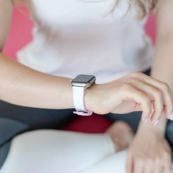 Pink Sand AW white rubber band on wrist of a woman runner with white shirt and a grey paint